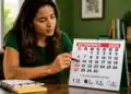 Mulher brasileira consultando calendário de setembro de 2026 em mesa de escritório, representando o planejamento do calendário completo de folgas.