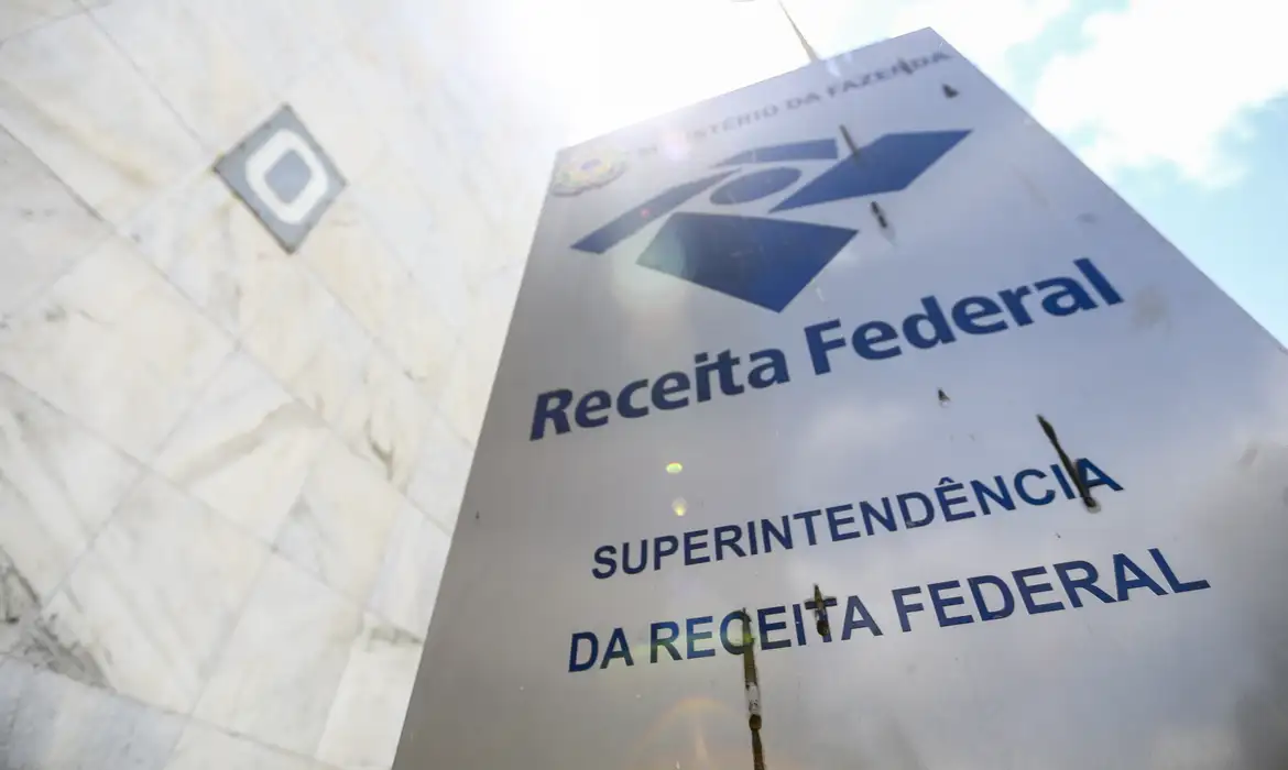 Receita Federal orienta cidadãos a denunciarem cobranças fraudulentas Fachada da Receita Federal onde o órgão alerta a população sobre golpes envolvendo cobranças falsas.
