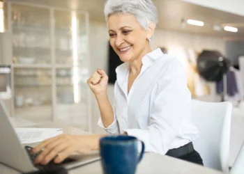 Mulher madura sorrindo enquanto trabalha no notebook, representando nova fase profissional após os 40 anos.