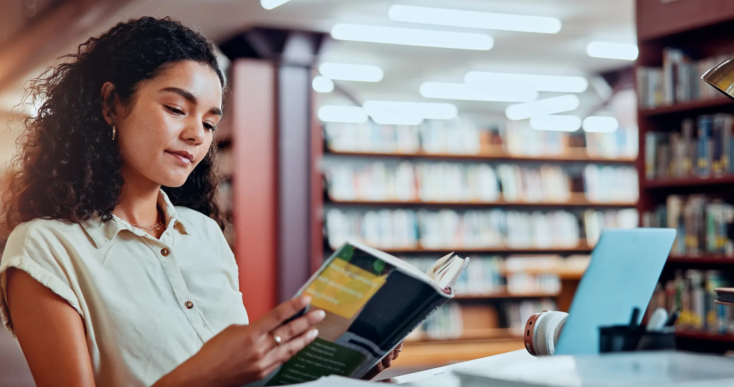 Aprofundamento na Pesquisa: Encontrando Fontes Confiáveis para o TCC Estudante lendo um livro de pesquisa na biblioteca, representando a fase de aprofundamento do TCC.
