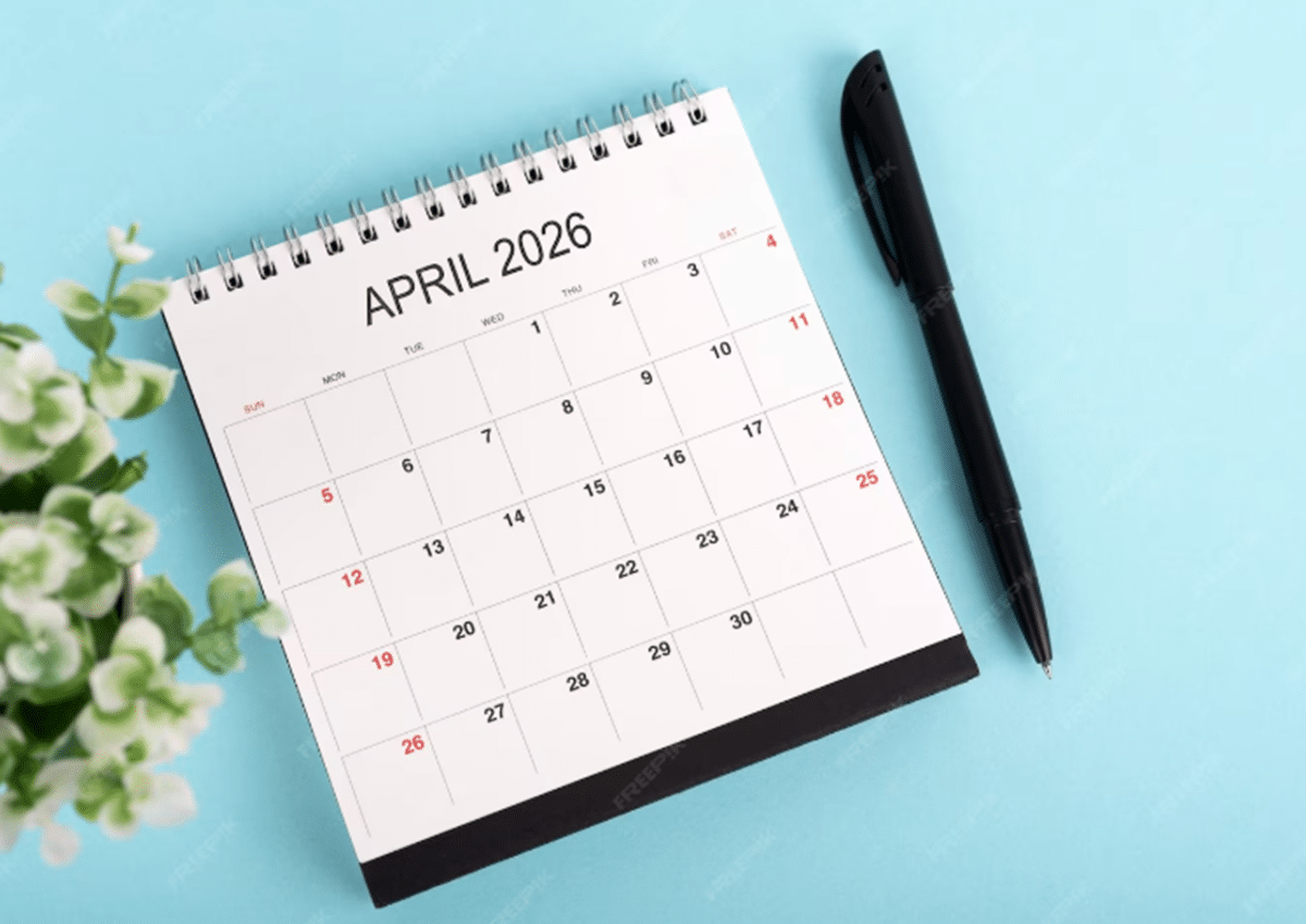 Calendário de abril 2026 com caneta e flores ao fundo — o que acontece no 1º de abril Dia da Mentira