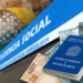 Carteira de trabalho azul sobre notas de reais, ao lado de fachada do INSS