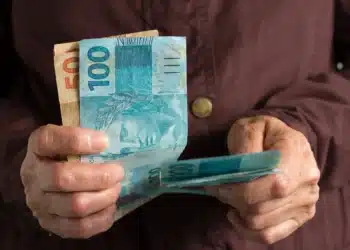 Idoso contando notas de real do benefício BPC referente ao calendário de pagamentos de março.