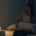 Mulher jovem asiática com dor de cabeça à noite, sofrendo de insônia enquanto tenta dormir em um ambiente com pouca luz. Estudo científico revela que dormir tarde pode afetar o coração a longo prazo.