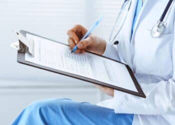 Médica preenchendo um formulário médico durante atendimento da perícia médica.