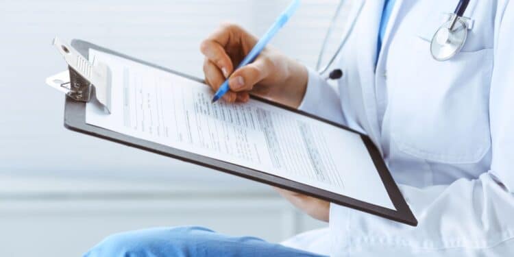 Médica preenchendo um formulário médico durante atendimento da perícia médica.