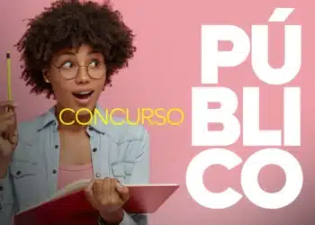 Jovem de óculos segurando lápis e caderno, com expressão surpresa, diante de fundo rosa.