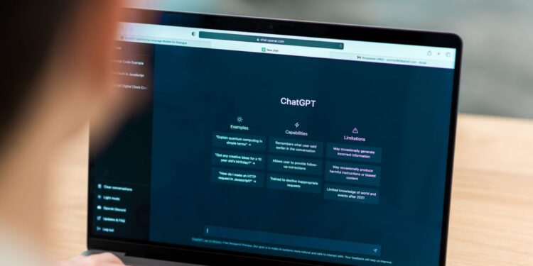 Pessoa utilizando laptop em uma mesa de madeira com a interface do ChatGPT aberta na tela, demonstrando o uso diário de inteligência artificial generativa.
