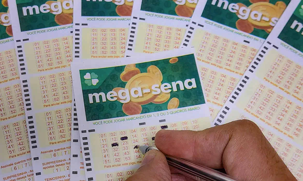 Cartões da Mega-Sena com números marcados, mostrando uma aposta sendo feita.