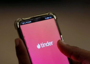 Tela inicial do aplicativo Tinder com o logo visível, destacando a interface com novos recursos de astrologia e química para encontrar o match ideal.