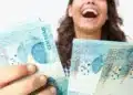 Pessoa segurando notas de real representando o pagamento do Abono Salarial 2026 para trabalhadores nascidos em setembro e outubro.
