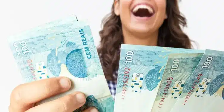 Pessoa segurando notas de real representando o pagamento do Abono Salarial 2026 para trabalhadores nascidos em setembro e outubro.