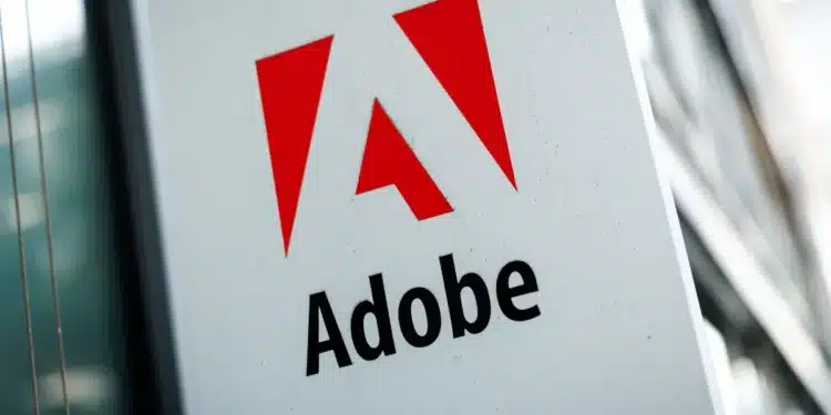 Logotipo da Adobe com o ícone "A" estilizado em vermelho e o nome da marca em preto, exibido em uma placa branca na fachada de um edifício moderno.