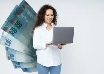 Profissional trabalhando no computador com dinheiro ao fundo, representando o crescimento salarial nas profissões de 2026.