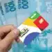 Cartão do programa Bolsa Família com cédulas de R$ 100 ao fundo, representando o pagamento do benefício.