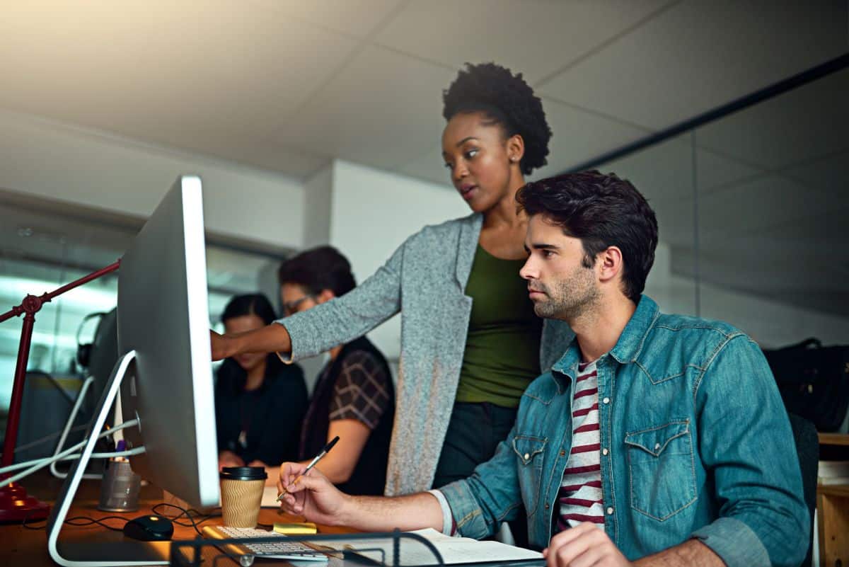 Profissionais de computação em ambiente de escritório, discutindo soluções tecnológicas e desenvolvimento de software.