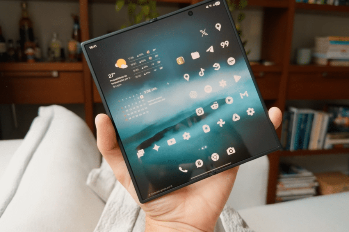 Mão segurando smartphone dobrável aberto, mostrando ícones de aplicativos e agenda na tela