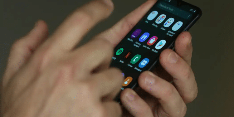 Mãos utilizando smartphone com aplicativos abertos na tela iluminada