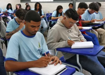 Alunos do ensino médio em sala de aula escrevendo em seus cadernos, representando a ideia de educação e o novo sistema do Inep para certificação do ensino médio.