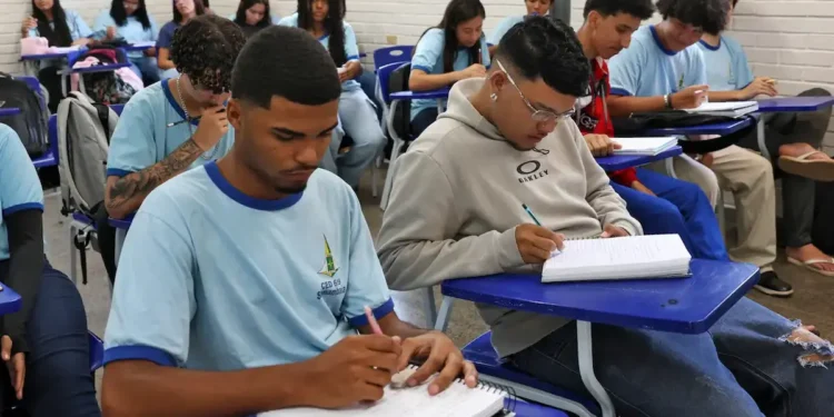 Alunos do ensino médio em sala de aula escrevendo em seus cadernos, representando a ideia de educação e o novo sistema do Inep para certificação do ensino médio.