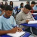 Alunos do ensino médio em sala de aula escrevendo em seus cadernos, representando a ideia de educação e o novo sistema do Inep para certificação do ensino médio.