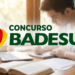Homem faz anotações em caderno ao lado de livros e notebook com logo do BADESUL