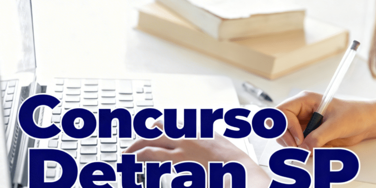 Mão digitando em notebook ao lado de caderno e caneta sobre mesa branca