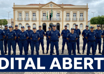 Grupo de guardas municipais uniformizados alinhados em praça diante de prédio histórico