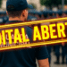 Grupo de guardas municipais perfilados com destaque para edital aberto em destaque amarelo