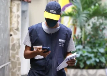 Imagem ilustrativa de um profissional do IBGE consultando documentos e o celular.