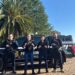 Quatro policiais civis fardados posando em frente a viaturas da Polícia Civil de Santa Catarina representando o concurso da PC SC 2026 com gabaritos e nota mínima para aprovação