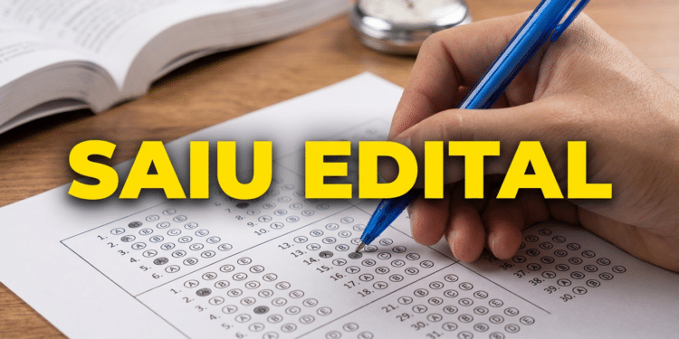 Mão marca alternativa em gabarito de prova objetiva com caneta azul e livro aberto ao fundo