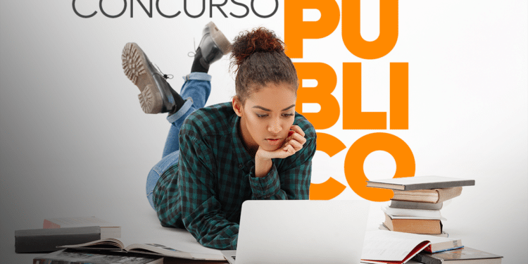 Estudante deitada no chão usando notebook cercada por livros e anotações