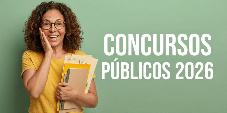 Mulher segurando cadernos e folders amarelos sorri diante de parede verde com texto Concursos Públicos 2026