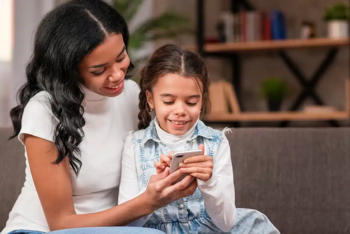 Mãe e filha interagindo com celular, mostrando o uso responsável do aparelho.