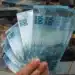 Notas de 100 reais representando o impacto econômico do pagamento antecipado do 13º salário do INSS
