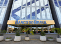 Prédio espelhado do Banco do Brasil com letreiro amarelo e plantas na entrada