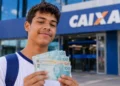 Estudante segura cédulas em frente a uma agência da Caixa, representando os pagamentos de agosto do Pé-de-Meia, encerrados nesta segunda-feira, 31.