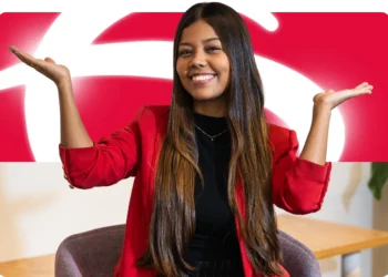 Jovem sorrindo com blazer vermelho na frente da logomarca do Bradesco — vagas de estágio e jovem aprendiz Bradesco 2026