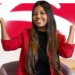 Jovem sorrindo com blazer vermelho na frente da logomarca do Bradesco — vagas de estágio e jovem aprendiz Bradesco 2026