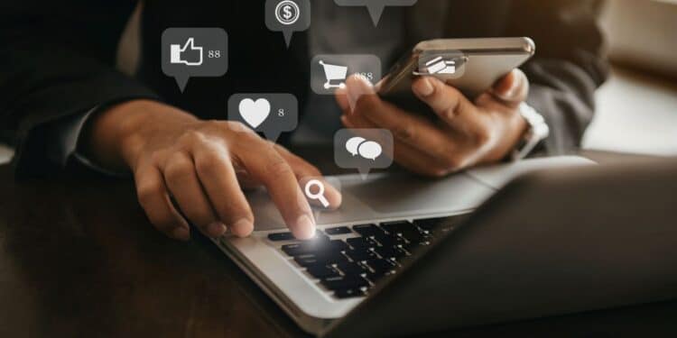 Pessoa utilizando notebook e smartphone enquanto acessa plataformas digitais relacionadas a marketing e vendas online.
