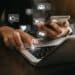 Pessoa utilizando notebook e smartphone enquanto acessa plataformas digitais relacionadas a marketing e vendas online.