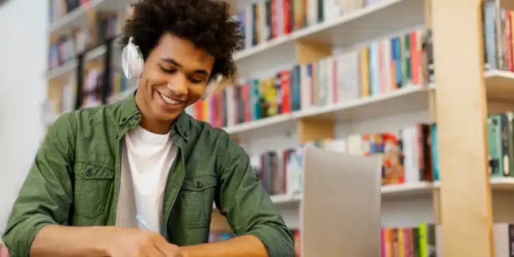Jovem sorrindo enquanto estuda para concursos públicos, usando fones de ouvido em uma biblioteca.