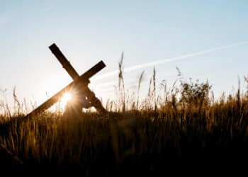 Pessoa carregando cruz de madeira em campo aberto ao entardecer — Sexta-feira Santa feriado nacional 2026