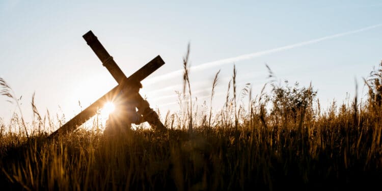 Pessoa carregando cruz de madeira em campo aberto ao entardecer — Sexta-feira Santa feriado nacional 2026