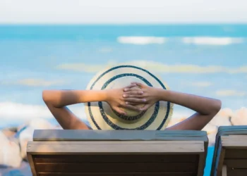 Pessoa relaxando em cadeira de praia observando o mar, representando o planejamento de viagens nos feriados de abril de 2026.