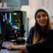 Mulher streamer jogando jogo de tiro espacial em seu computador com teclados RGB e ambiente de estúdio.