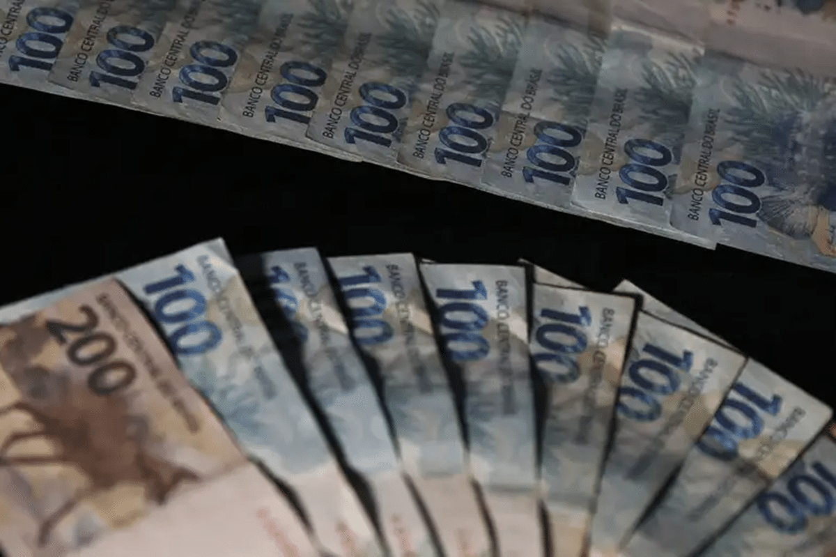 Notas de cem e duzentos reais espalhadas — pagamento INSS acima do salário mínimo 2026