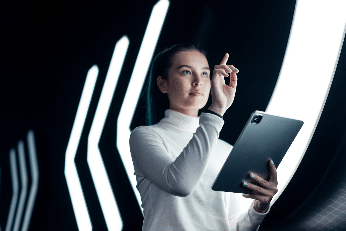Mulher utiliza tablet e faz gesto de toque em interface digital iluminada