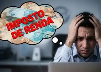 Homem preocupado segurando a cabeça diante do computador pensando no Imposto de Renda com notas de dinheiro ao fundo